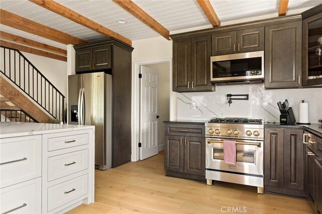 27684 St Bernard Ln, Lake Arrowhead, CA 92352 - kitchen with appliances with stainless steel finishes, beam ceiling, dark brown cabinetry, light wood-type flooring, and tasteful backsplash