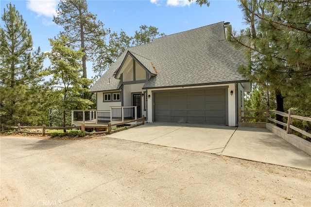 27684 St Bernard Ln, Lake Arrowhead, CA 92352 - view of front facade with roof with shingles, an attached garage, driveway, and a wooden deck