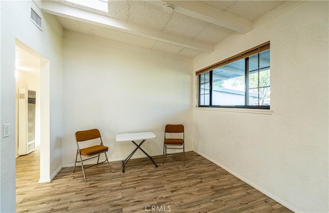 sitting room featuring wood finished floors, beamed ceiling, baseboards, and visible vents