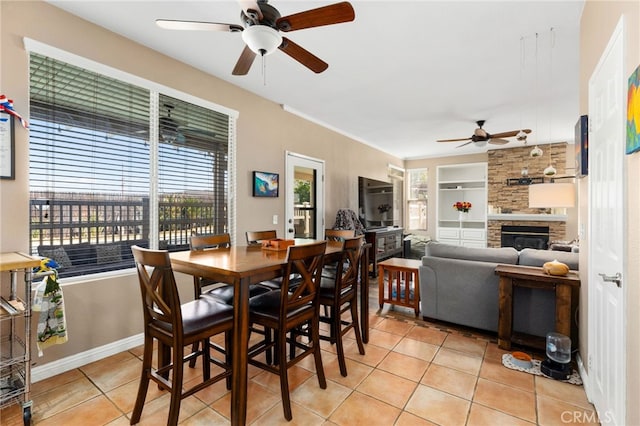 27196 Swift St, Menifee, CA 92584 - dining area featuring a ceiling fan, light tile patterned flooring, a fireplace, built in features, and baseboards
