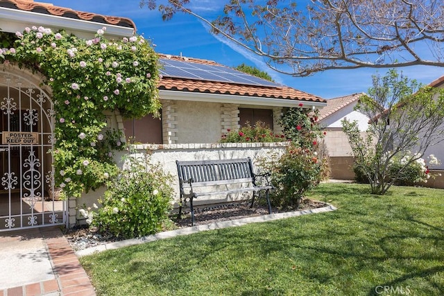 1130 Carob Ct, Hemet, CA 92545 - view of front of home with a tiled roof, stucco siding, roof mounted solar panels, a front lawn, and a gate