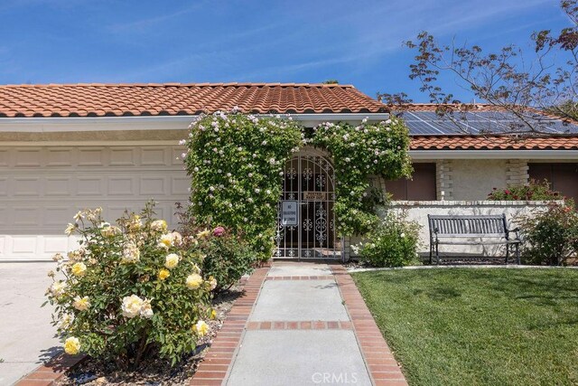 1130 Carob Ct, Hemet, CA 92545 - view of front of house featuring a tile roof, a garage, solar panels, a front lawn, and stucco siding
