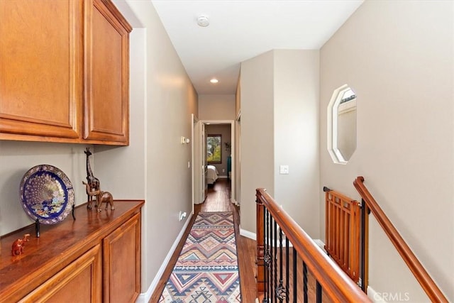hall featuring baseboards, recessed lighting, wood finished floors, and an upstairs landing