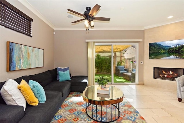 living area featuring a fireplace, crown molding, tile patterned flooring, and a ceiling fan