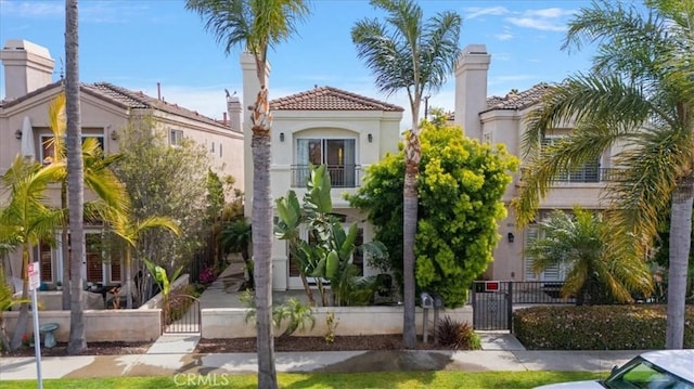 mediterranean / spanish home with a gate, stucco siding, a fenced front yard, and a tiled roof