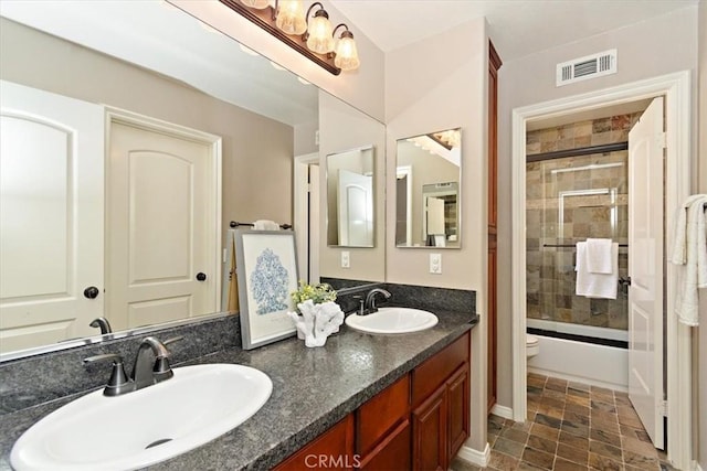 bathroom with visible vents, shower / bath combination with glass door, double vanity, and a sink