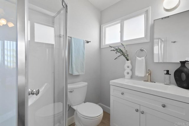 full bath featuring a shower stall, vanity, baseboards, and toilet