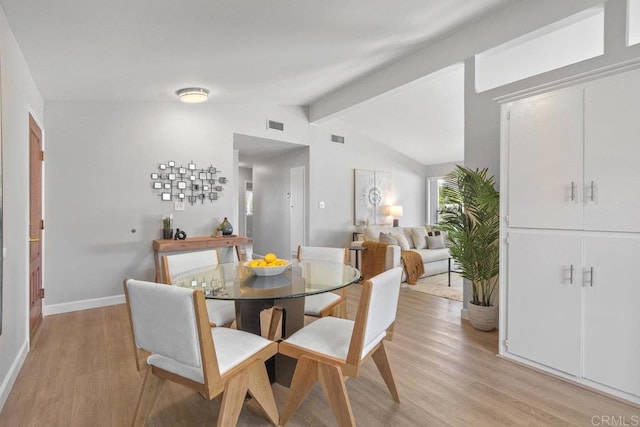 dining room featuring light wood-style flooring, baseboards, vaulted ceiling with beams, and visible vents