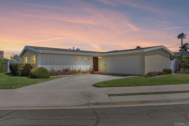 ranch-style home featuring board and batten siding, a yard, stucco siding, a garage, and concrete driveway