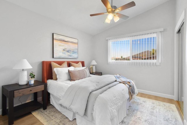 bedroom with ceiling fan, a closet, wood finished floors, lofted ceiling, and baseboards