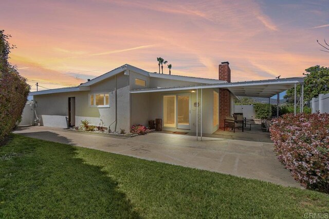 6065 Zora St, La Mesa, CA 91942 - back of house at dusk with a chimney, a patio, and stucco siding