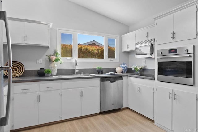 6065 Zora St, La Mesa, CA 91942 - kitchen featuring appliances with stainless steel finishes, a sink, lofted ceiling, dark countertops, and white cabinets