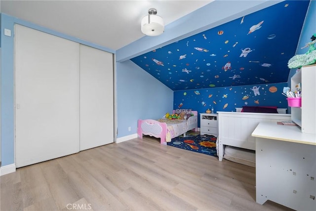 bedroom featuring baseboards, wood finished floors, lofted ceiling with beams, and a closet