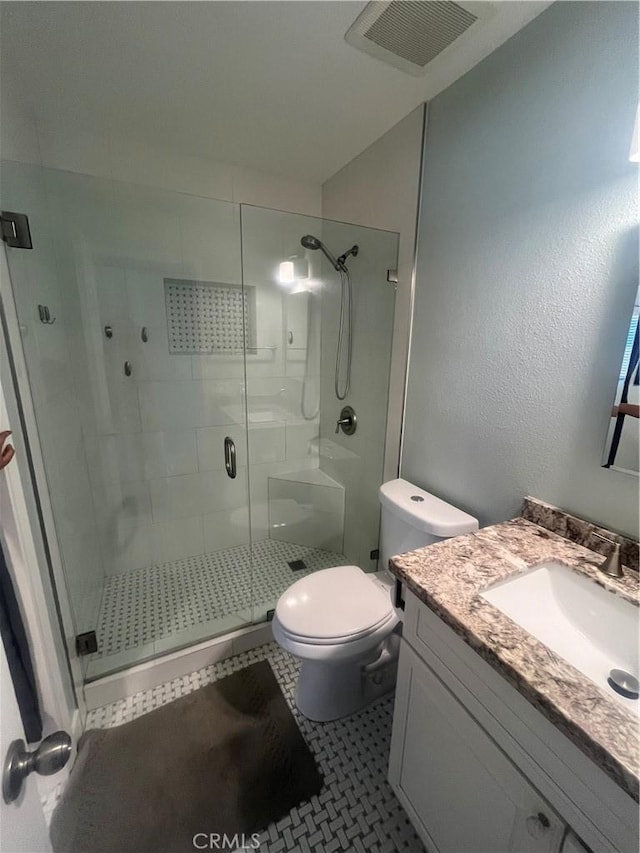 full bathroom featuring a shower stall, visible vents, toilet, tile patterned floors, and vanity