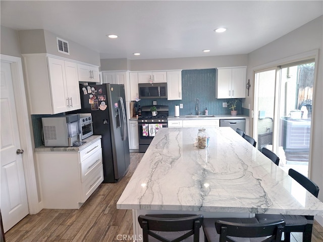 kitchen featuring tasteful backsplash, white cabinets, a sink, visible vents, and stainless steel appliances
