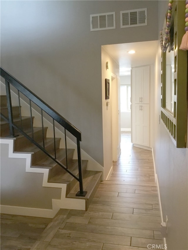 stairway featuring baseboards, visible vents, and wood finished floors