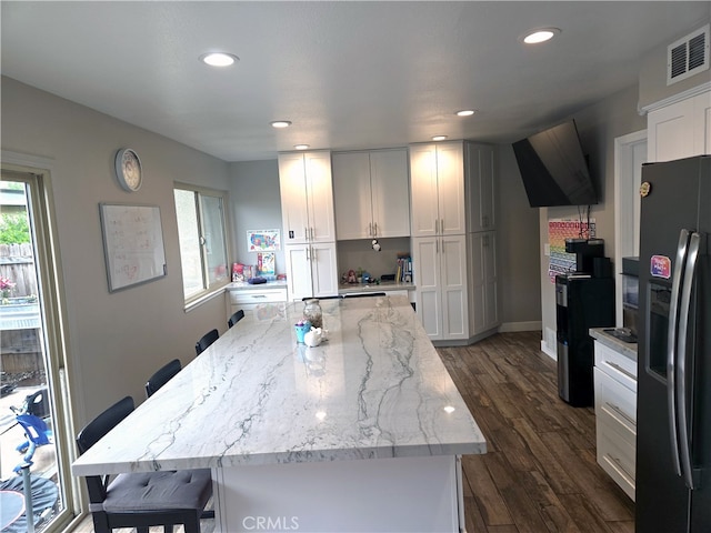 kitchen featuring recessed lighting, black fridge with ice dispenser, dark wood-type flooring, visible vents, and white cabinetry