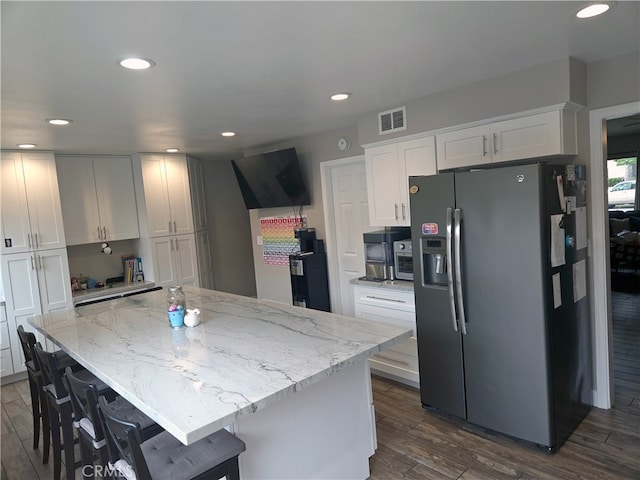 kitchen with stainless steel refrigerator with ice dispenser, visible vents, white cabinets, and dark wood-style flooring
