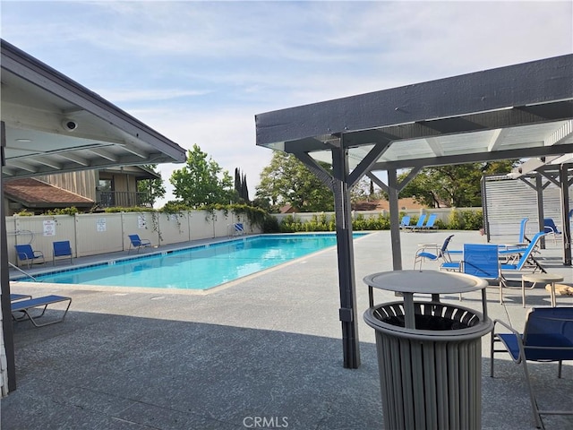 community pool with fence and a patio area