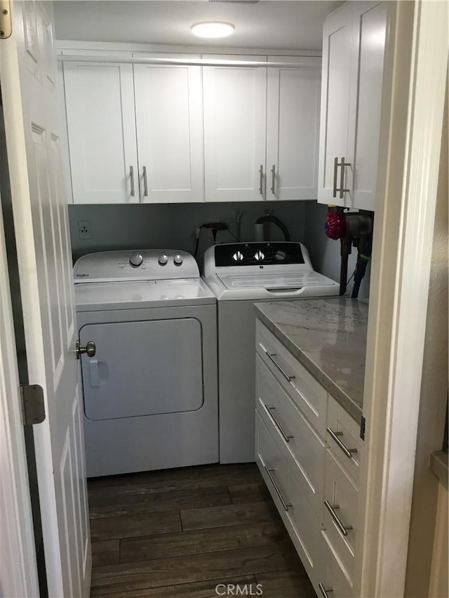 laundry area with dark wood-type flooring, washer and dryer, and cabinet space