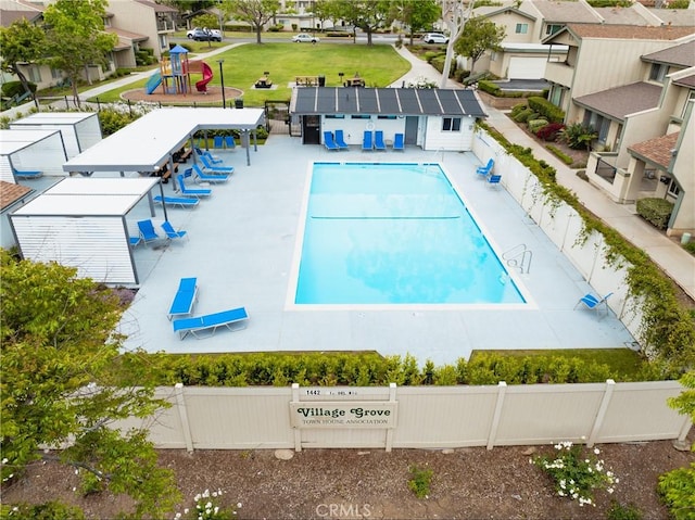 community pool featuring a patio, fence, and playground community