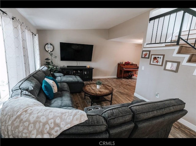 living area featuring baseboards, wood finished floors, and a healthy amount of sunlight