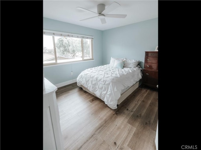 bedroom with a ceiling fan, wood finished floors, and baseboards