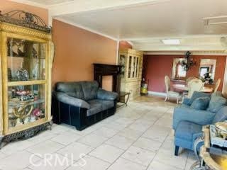 living area with ornamental molding and tile patterned flooring