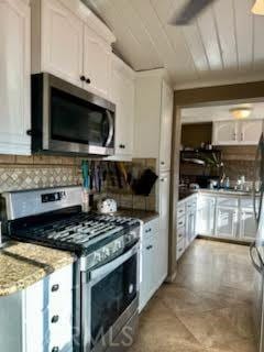 kitchen with tasteful backsplash, white cabinets, light stone counters, and stainless steel appliances