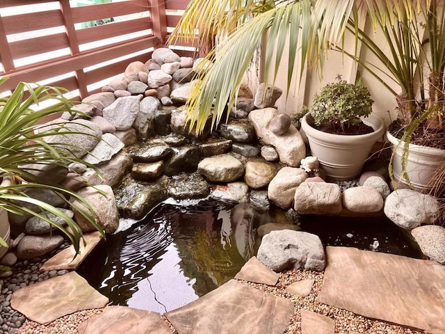 details featuring fence and a garden pond