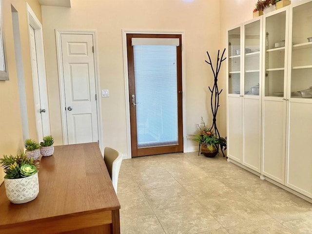 doorway to outside with baseboards and light tile patterned flooring