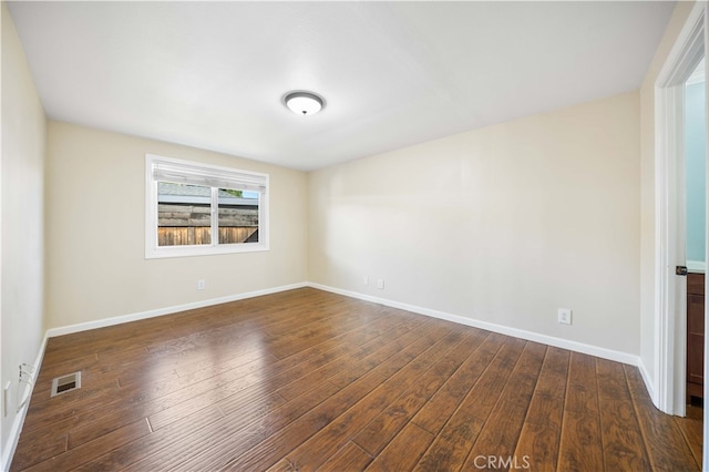 spare room featuring dark wood-type flooring, baseboards, and visible vents