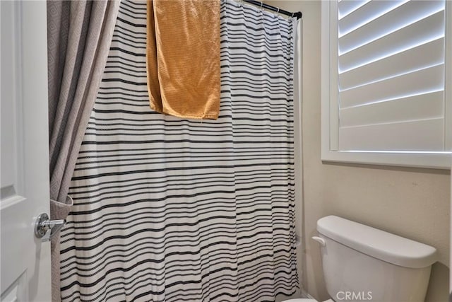 bathroom featuring toilet and a shower with shower curtain