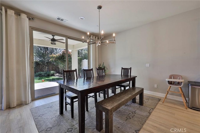 dining area with visible vents, baseboards, light wood-style floors, and ceiling fan with notable chandelier