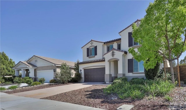 mediterranean / spanish home featuring a tiled roof, driveway, stucco siding, and a garage
