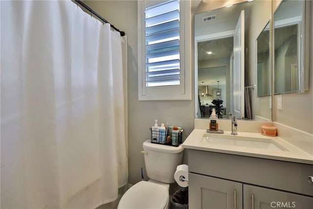full bathroom featuring toilet, vanity, visible vents, and a shower with curtain