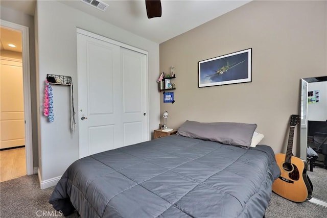 carpeted bedroom with a closet, baseboards, a ceiling fan, and visible vents