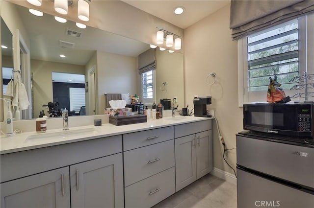bathroom featuring visible vents, a sink, tile patterned floors, double vanity, and baseboards