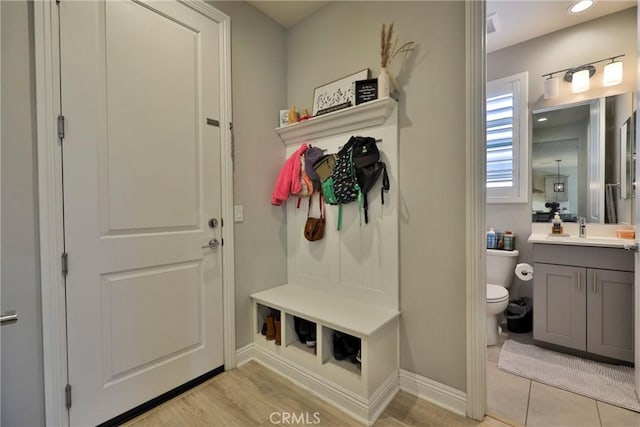 mudroom featuring recessed lighting, light wood finished floors, baseboards, and a sink