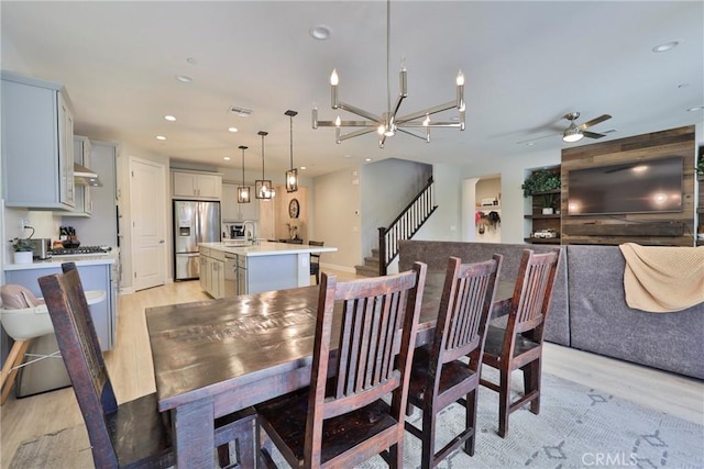 dining area featuring light wood-style floors, ceiling fan with notable chandelier, and recessed lighting