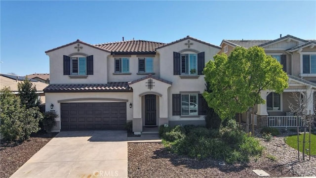 mediterranean / spanish house featuring a tiled roof, stucco siding, a garage, and concrete driveway