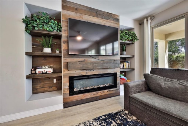 living area with wood finished floors, baseboards, and a glass covered fireplace