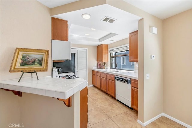 kitchen with light tile patterned flooring, visible vents, a kitchen bar, and white dishwasher
