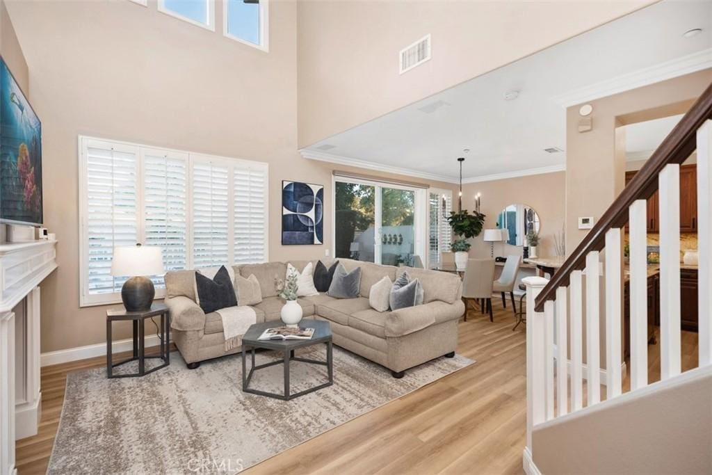 living area with wood finished floors, ornamental molding, visible vents, and a wealth of natural light