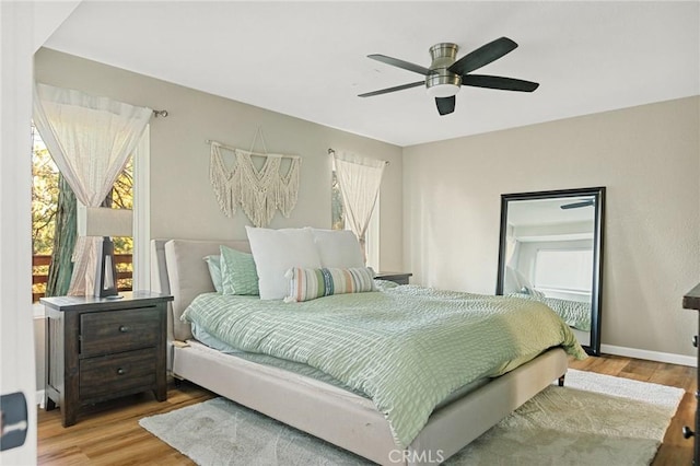 bedroom with ceiling fan, wood finished floors, and baseboards