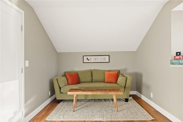 living area with lofted ceiling, baseboards, and wood finished floors