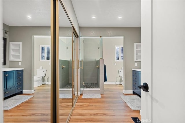 bathroom with toilet, a shower stall, vanity, and baseboards