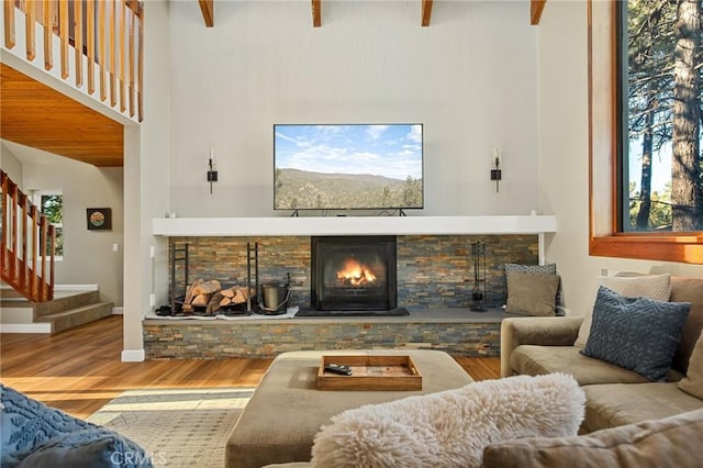 living room featuring baseboards, a fireplace, a high ceiling, stairs, and wood finished floors