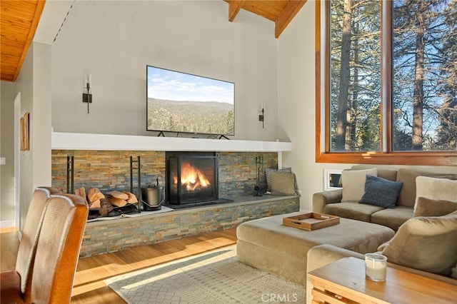 living area featuring high vaulted ceiling, a stone fireplace, wooden ceiling, wood finished floors, and beam ceiling