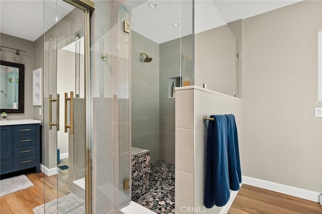 full bathroom with a stall shower, wood finished floors, and baseboards